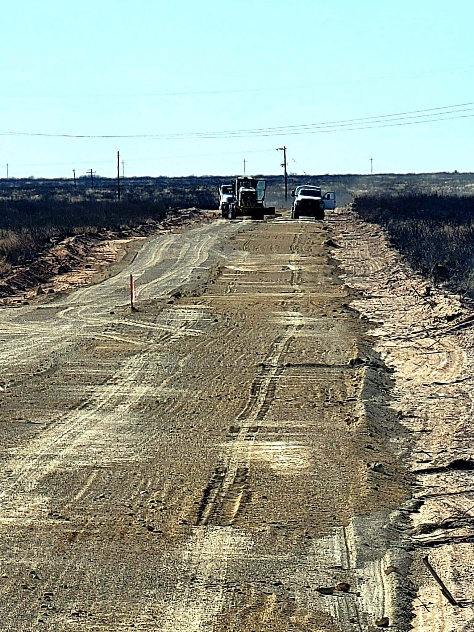 Rangefinder Excavation road grading crew and trucks on a Permian Basin job site