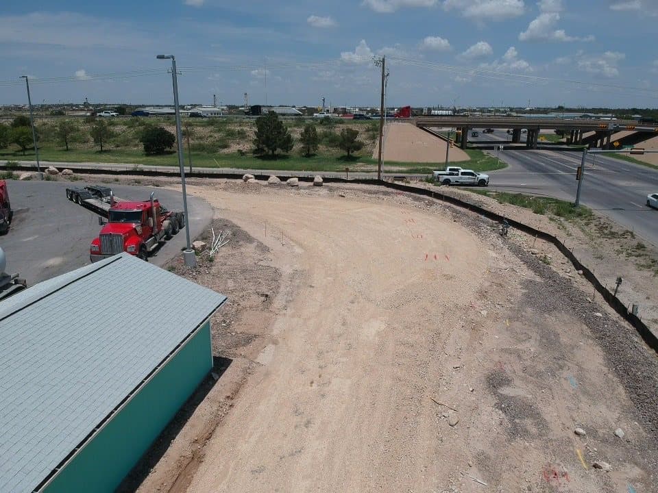 Aerial view of a detention area holding water beside new asphalt after a storm