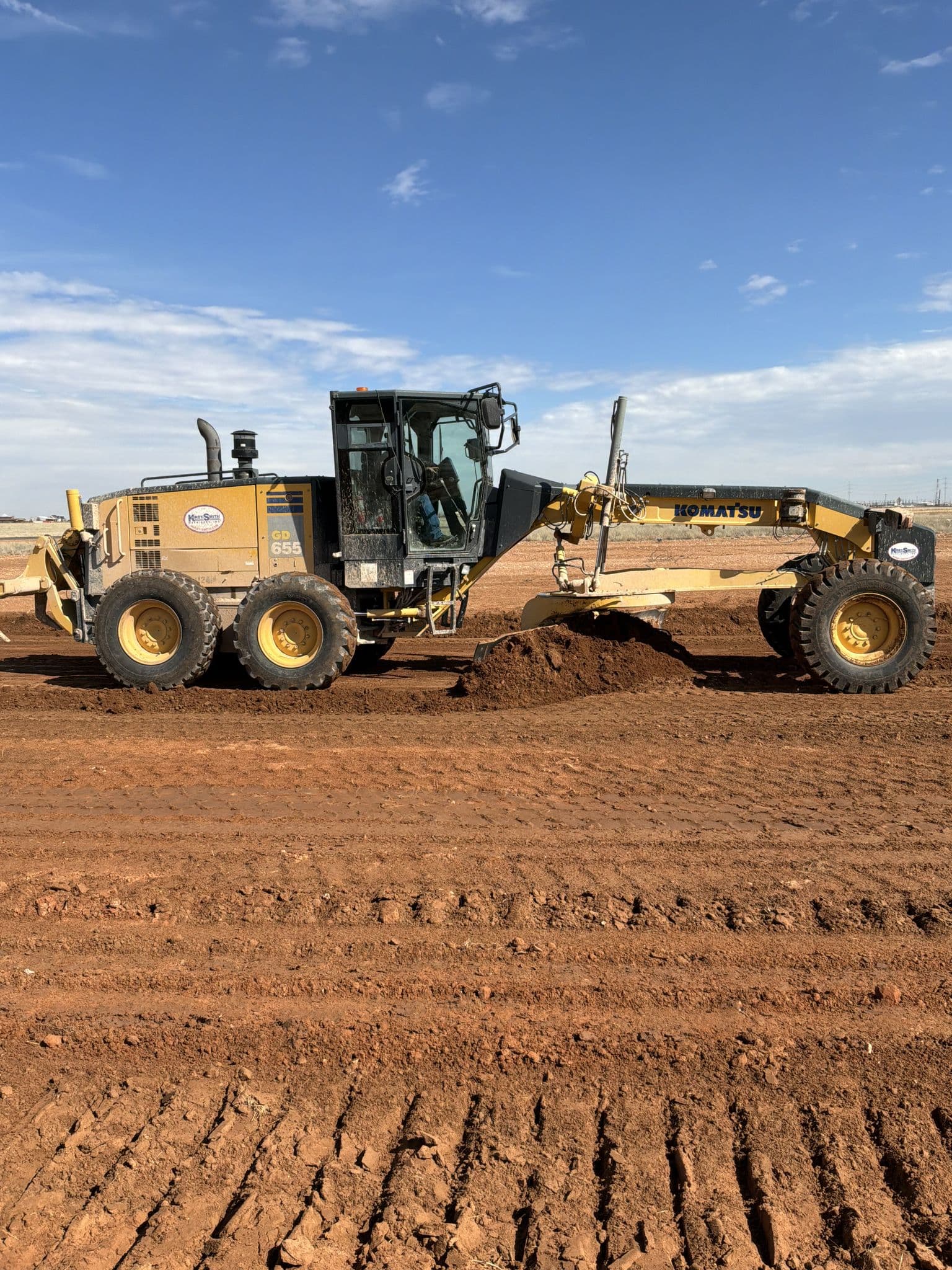 Motor grader making a finish pass across a commercial building pad in Midland, TX