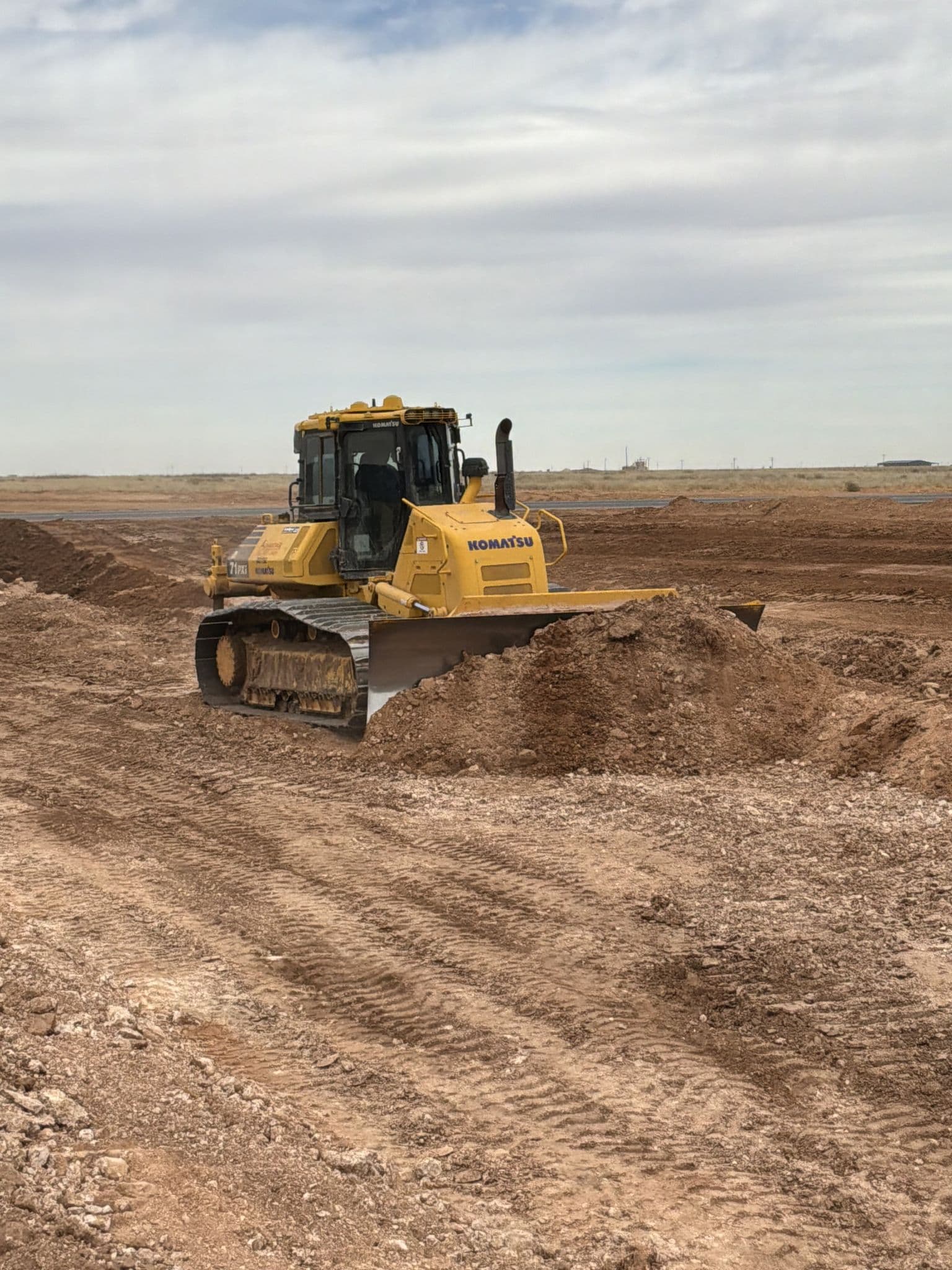 Dozer spreading fill across a commercial pad site on the West Texas plains