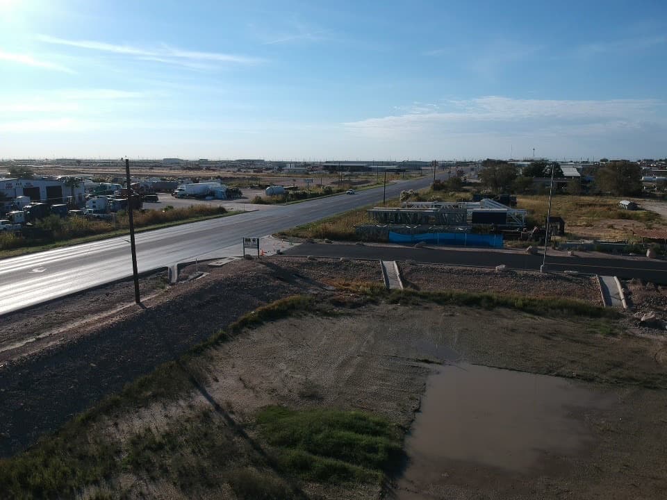 Aerial view of a raw commercial tract rough-graded along a Texas highway frontage