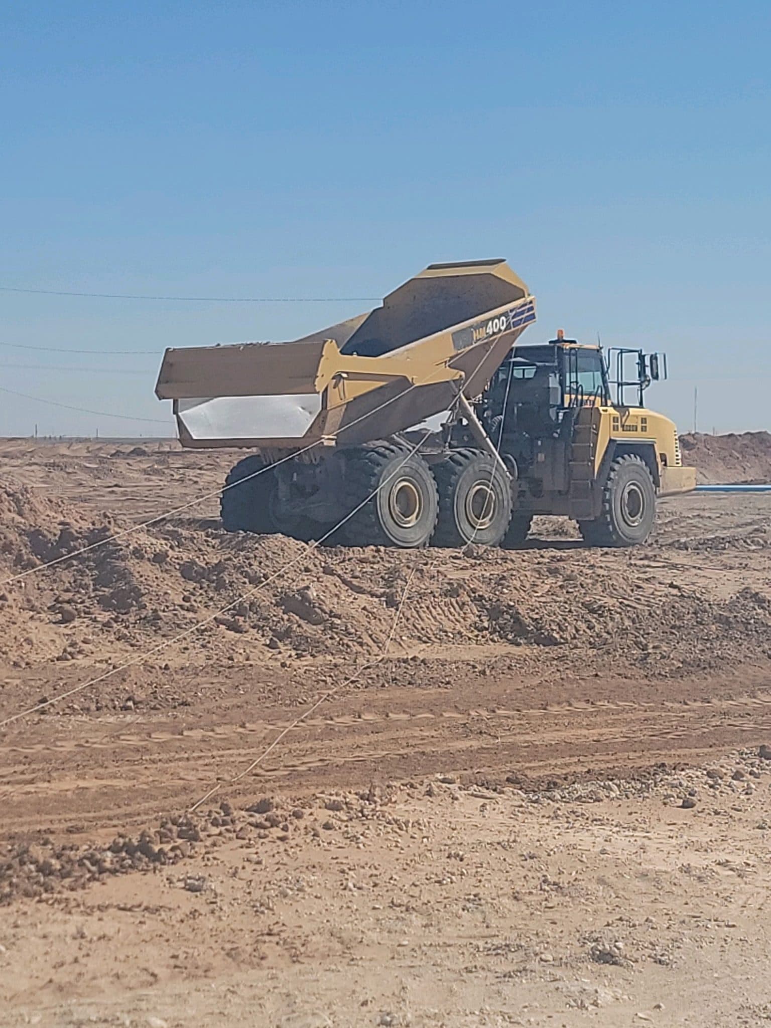 Articulated haul truck placing material during pond and dam construction