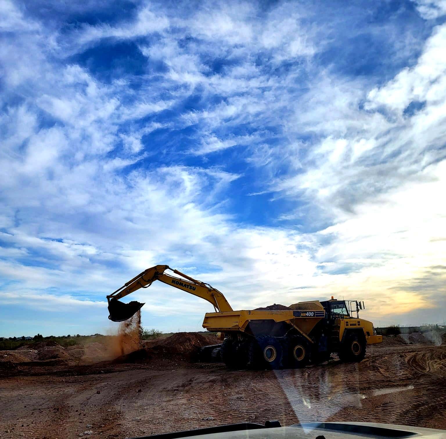 Excavator loading a haul truck on a Permian Basin job site