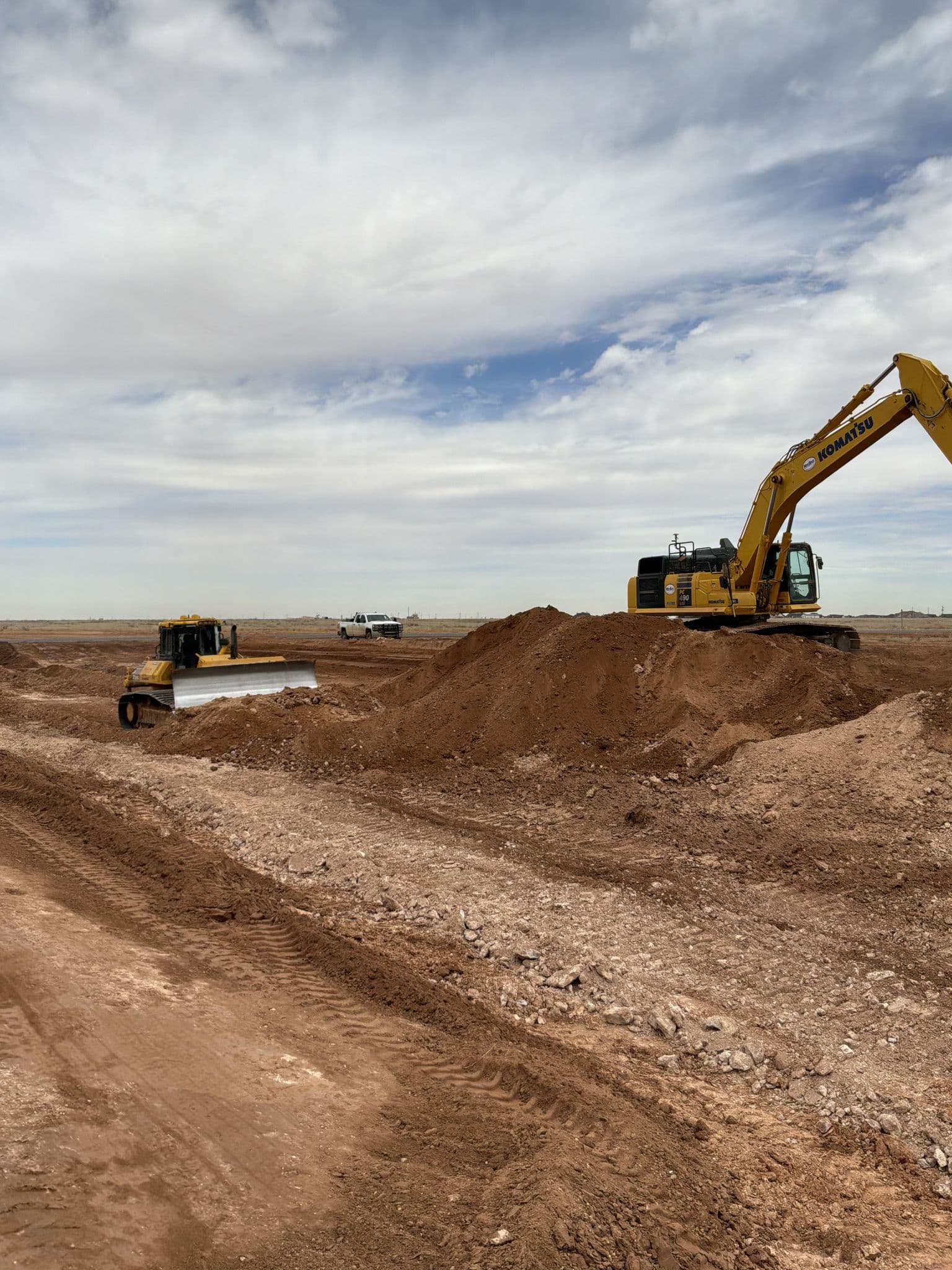 Wide view of a development site with a dozer and excavator cutting to grade
