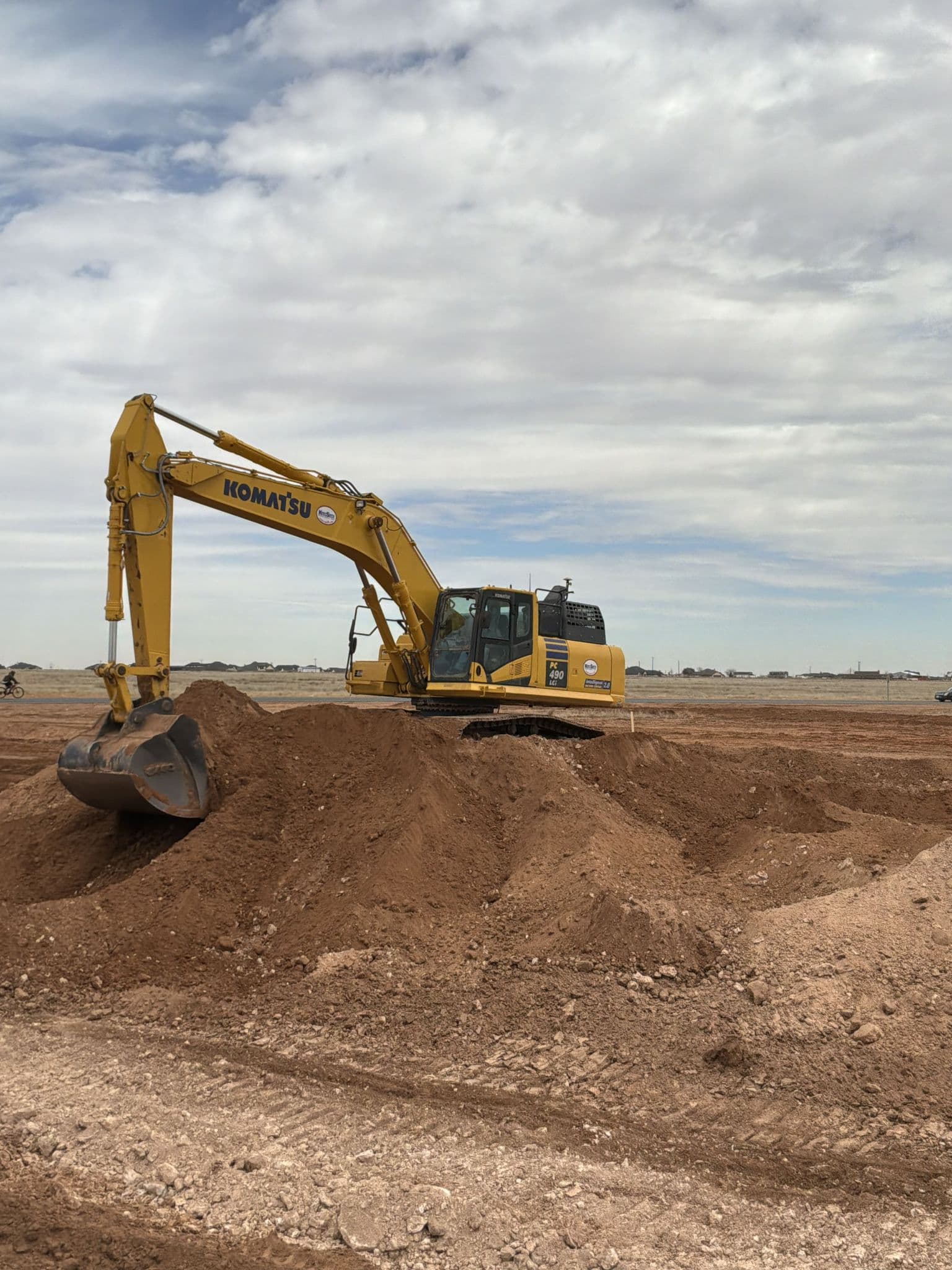 Excavator working a stockpile of cut material on a development site