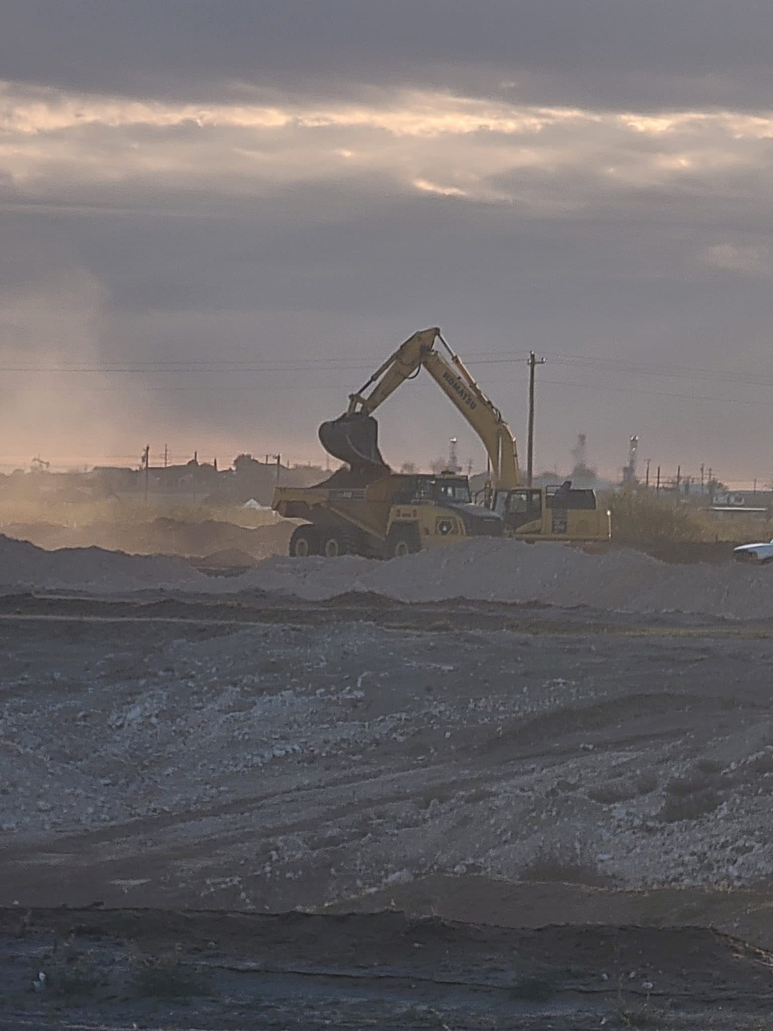 Excavator working a land development site in dusty conditions