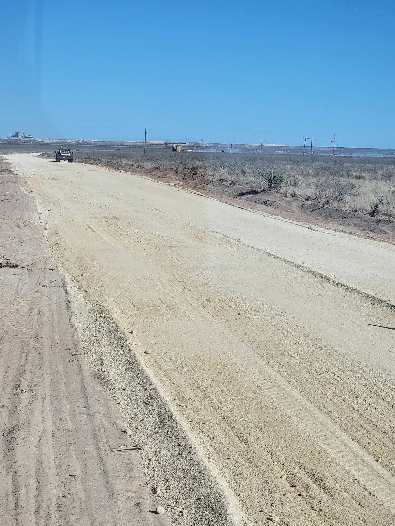 Freshly graded caliche driveway surface, compacted and crowned for drainage