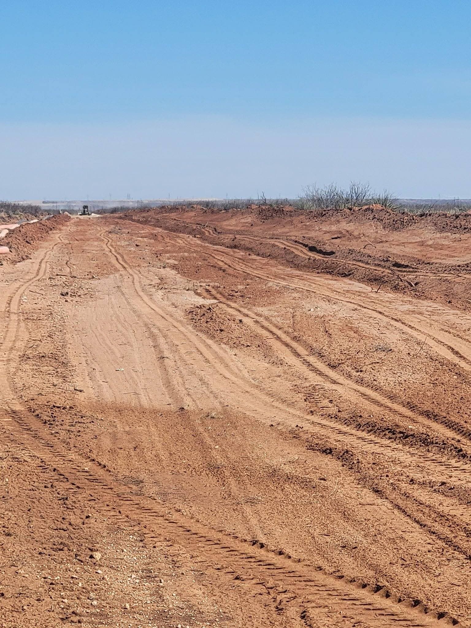 Graded dirt road cutting across open West Texas rangeland